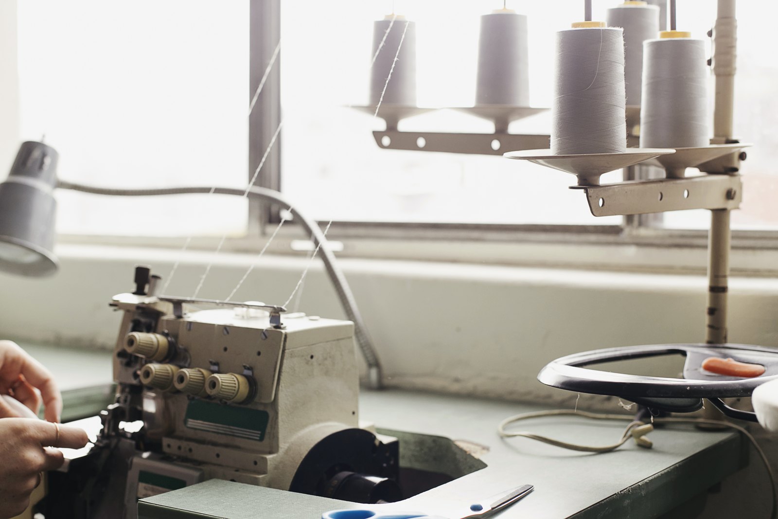 Sewing machine with thread cones and a tailor’s hands